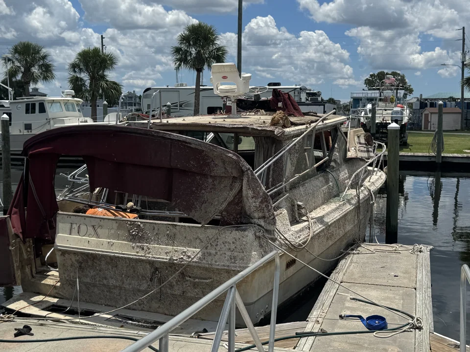 Aged cabin boat with an exposed stern alongside a dock
