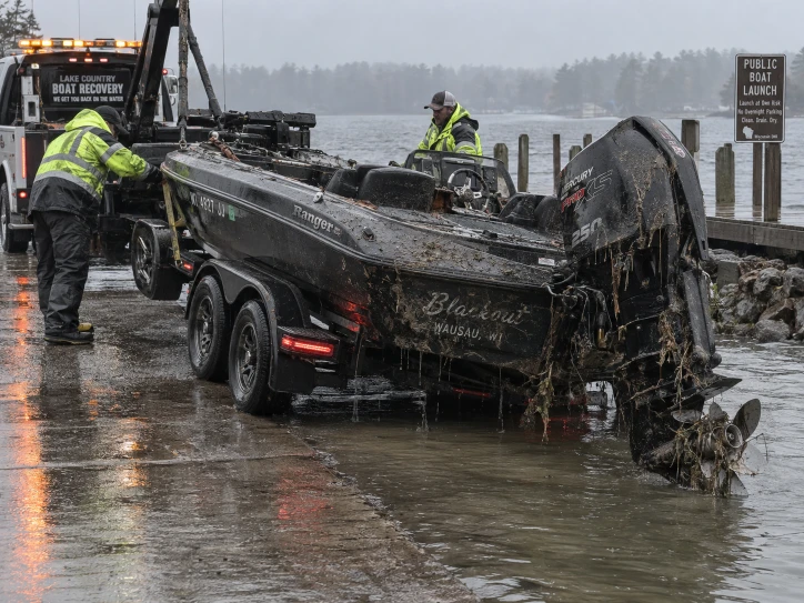 Mud-covered fishing boat on a trailer with lifting equipment at a wet ramp