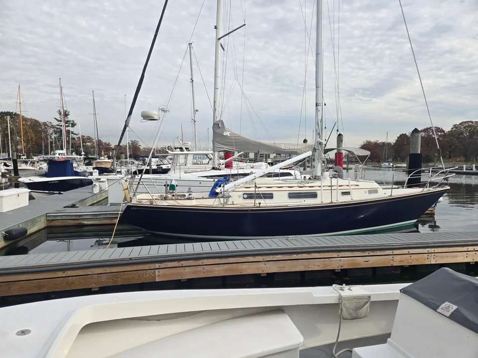 Blue-hulled sailboat moored alongside neighboring vessels