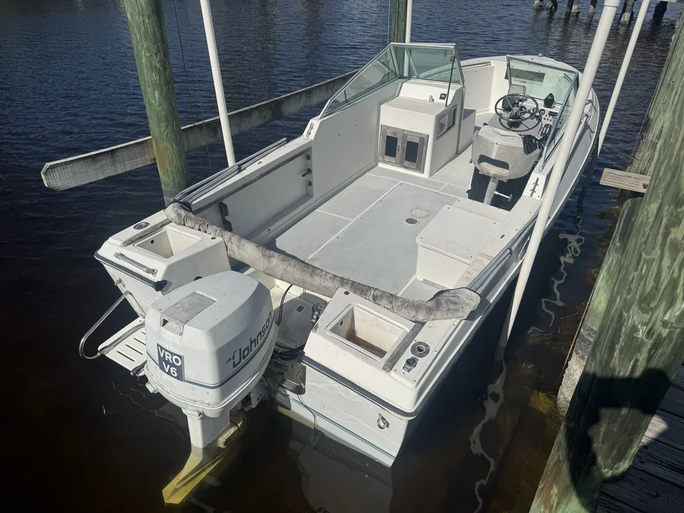 Center-console fishing boat with an outboard motor beside dock pilings
