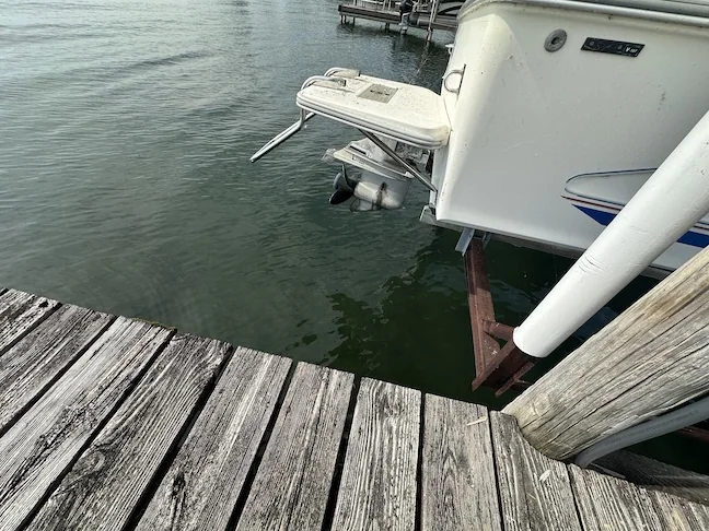 Close view of an outboard motor above the water beside a dock