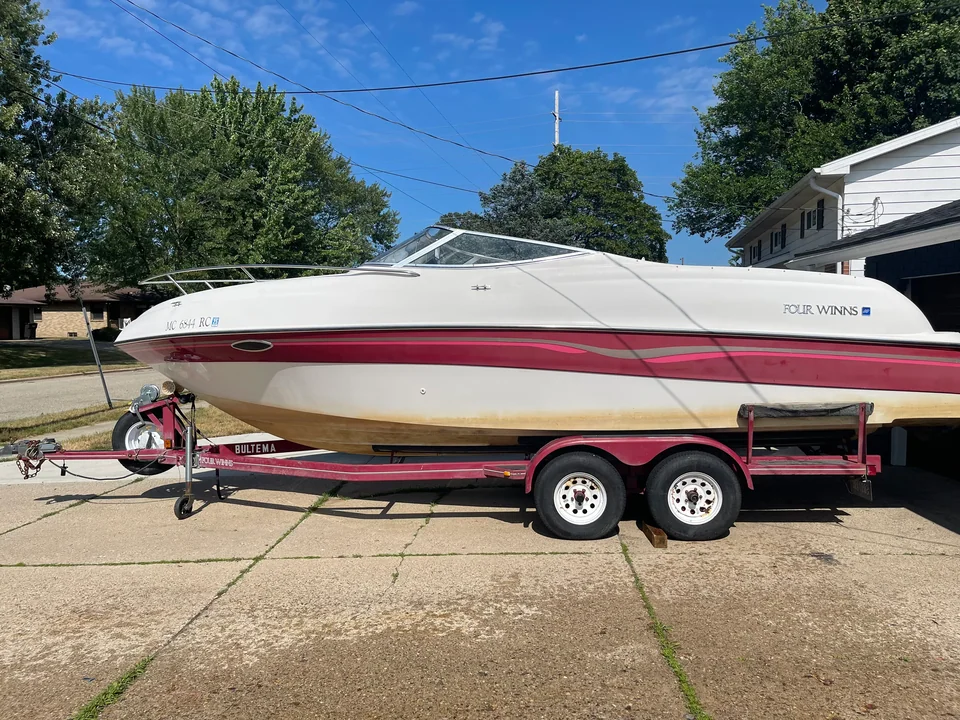 Covered red-striped motorboat on a tandem-axle trailer