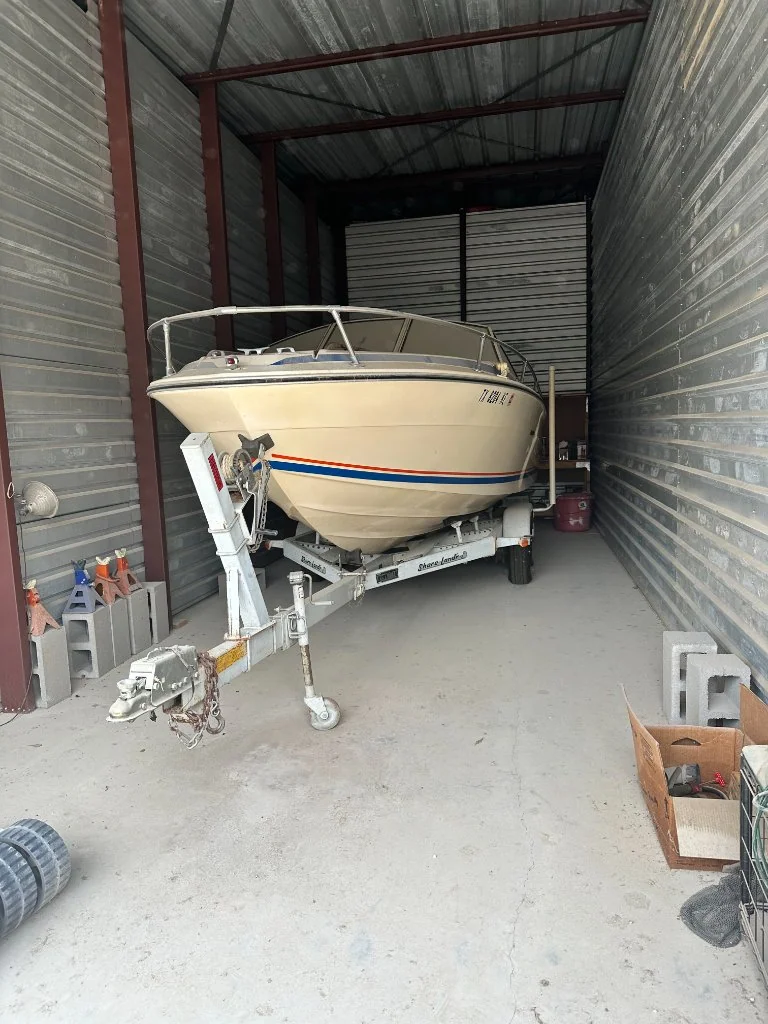 Cream-colored motorboat and trailer inside a storage unit