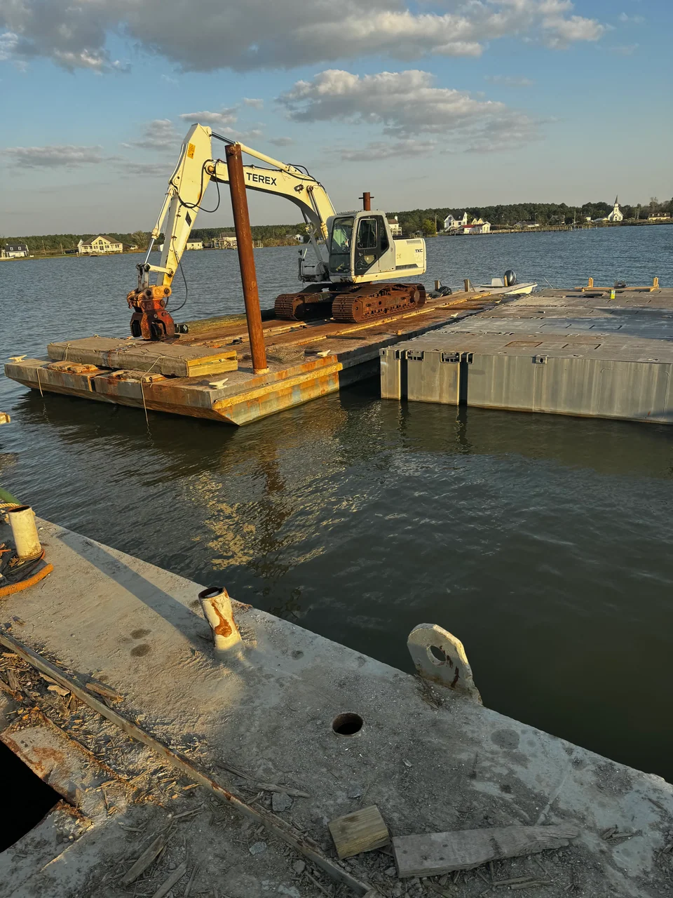 Excavator on a floating work platform near the shore