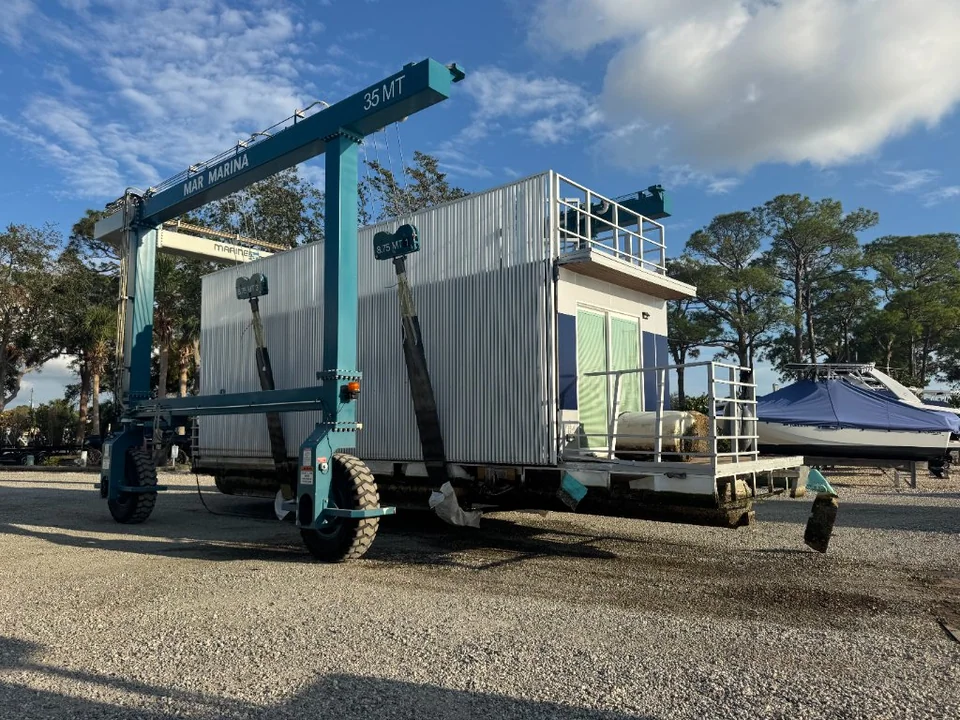 Large houseboat carried beneath a wheeled boatyard gantry