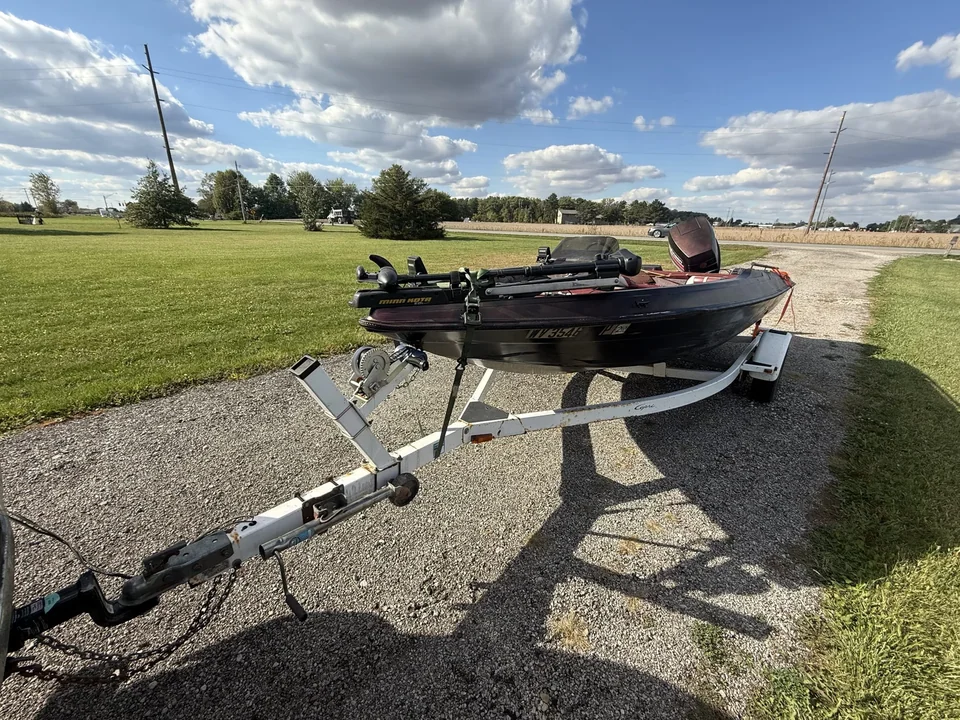 Low-profile fishing boat on a trailer beside an open field