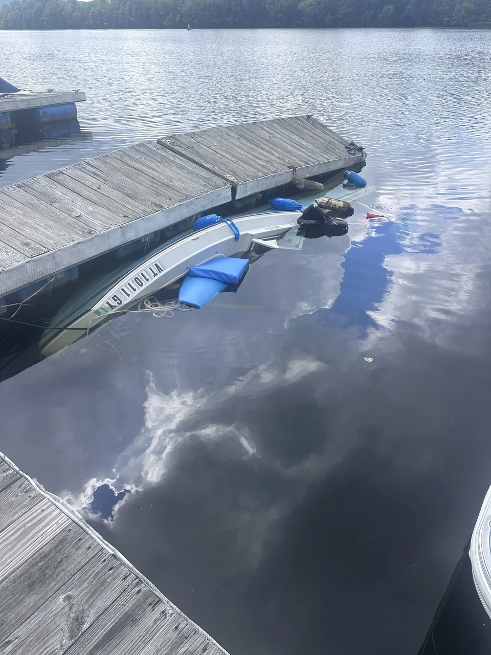 Partially submerged small boat beside a floating dock