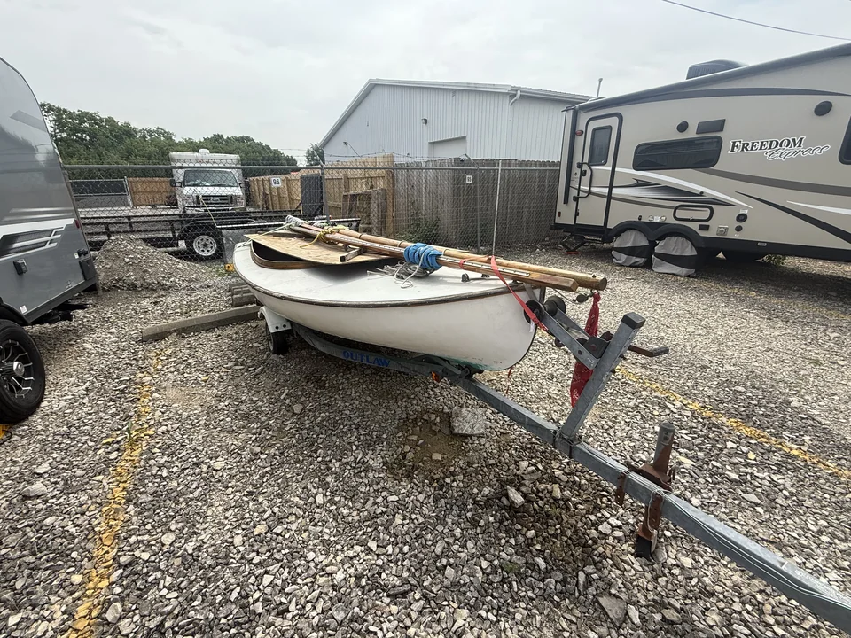 Small sailing dinghy on a trailer in a gravel storage yard
